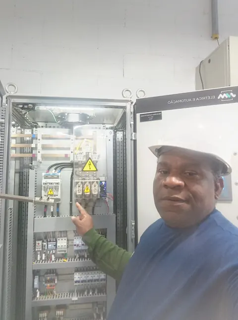 Profissional ao lado de um painel elétrico industrial aberto.