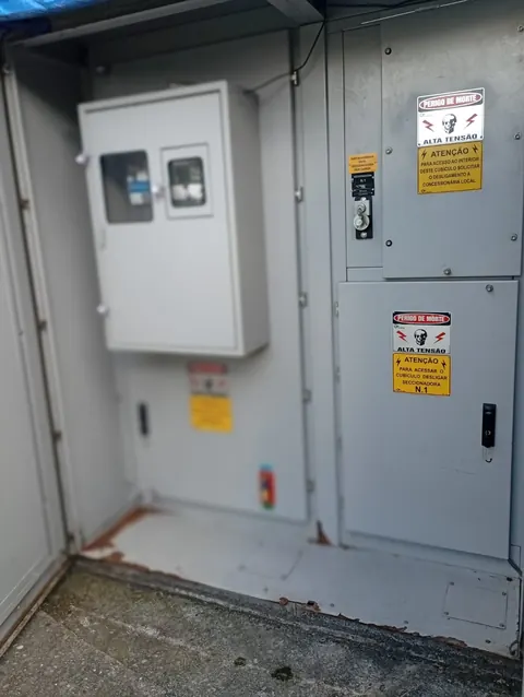 Cubículos de uma cabine elétrica com sinalização de alta tensão.
