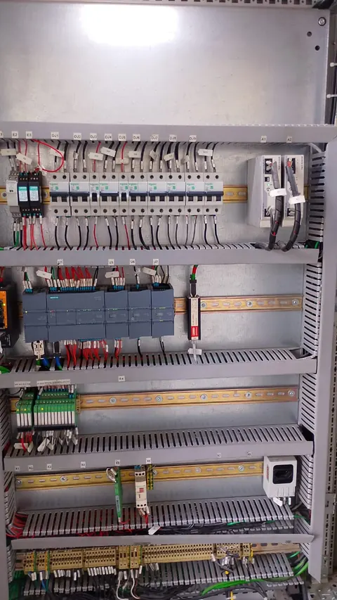 Controlador lógico programável, disjuntores e conexões no interior de um painel.