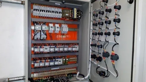 Painel aberto com disjuntores, contatores, bornes e comandos instalados na porta.